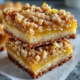 Freshly baked Homemade Lemon Crumb Bars showcase golden crumbles topping a vibrant, sunny yellow lemon filling in a square pan.