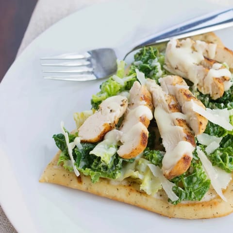 A close-up of Chicken Caesar Flatbread with juicy grilled chicken, fresh romaine, and a generous sprinkle of parmesan.
