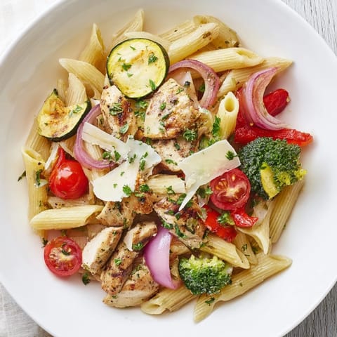 A close-up of savory Garlic Herb Chicken & Veg Pasta showcases juicy sliced chicken, vibrant veggies, and fresh parsley garnish on a warm plate.  