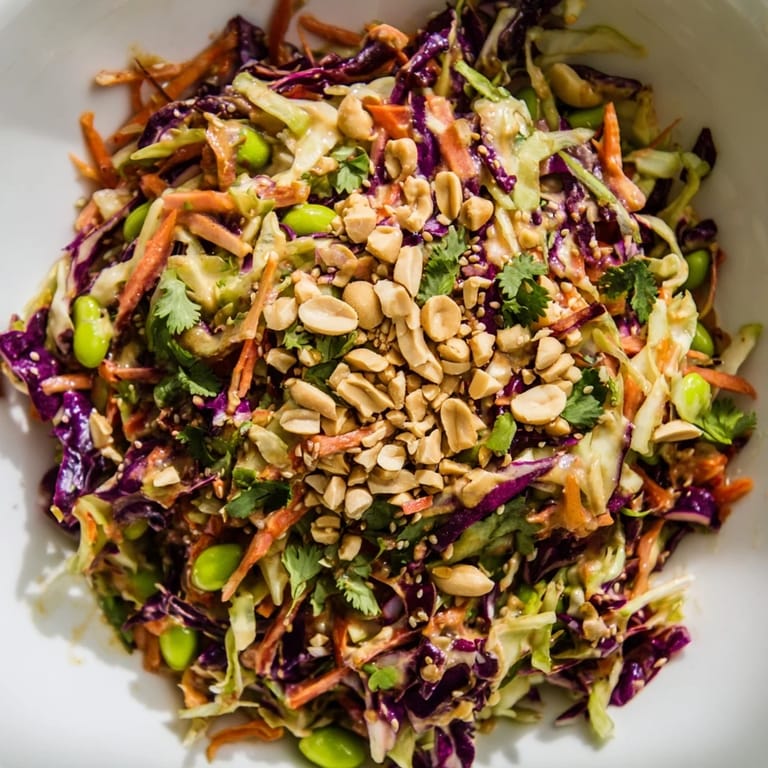 Colorful bowl of Crunchy Thai Peanut Salad topped with chopped peanuts and cilantro, ready for a refreshing light meal.  