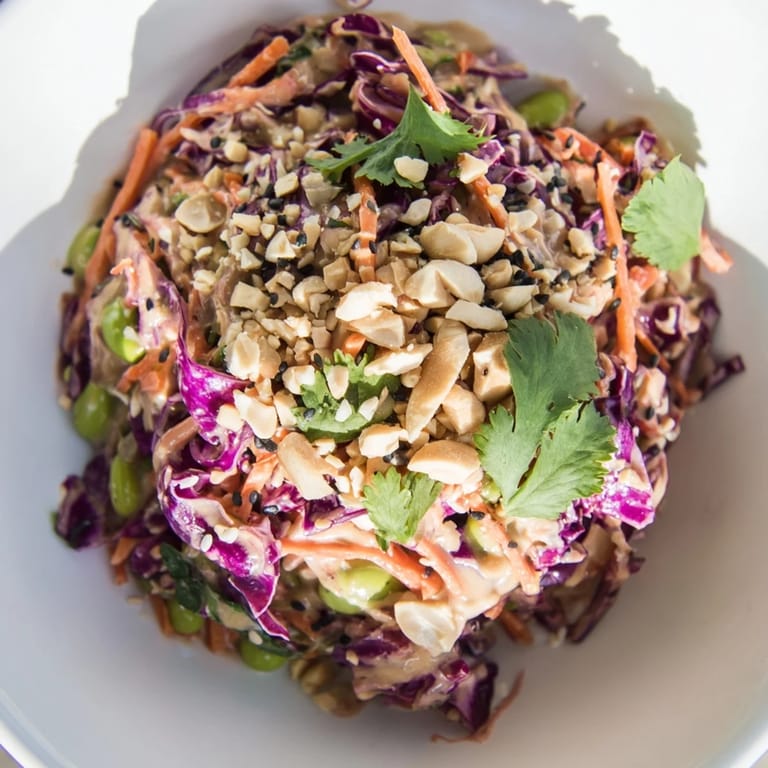 A close-up of Crunchy Thai Peanut Salad showing crunchy vegetables and sesame seeds drizzled with tangy ginger-lime dressing.